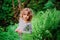 Cute child girl on the walk in summer woods with ferns