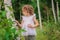 Cute child girl walking in summer forest with birch trees. Nature exploration with kids.