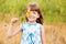 Cute child girl wear dress with sunflower in summer field. Happy little girl hide eye with sunflower. Summer holidays