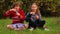 Cute child girls sits on grass with crossed legs and blowing soap bubbles in park. Playing with soap bubbles