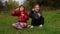 Cute child girls sits on grass with crossed legs and blowing soap bubbles in park. Playing with soap bubbles