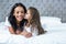 Cute child kissing her mother on the bed