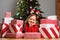 A cute child lies on the floor against the background of a Christmas tree and gifts. Dreamy little girl smiling