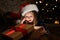 Cute child opening magic gift box near Christmas tree