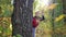 A cute child peeks from behind a tree in the Park