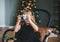 A cute child photographs you on a retro camera against the background of Christmas tree with balls