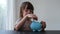 Cute child and piggy bank at home