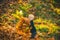 Cute child playing with autumn leaves. Happy child throwing the fallen leaves up, playing in the autumn park. Happy