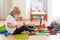 Cute child, playing with colorful toy blocks. Little boy building house of block toys sitting on the floor in sunny spacious