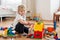 Cute child, playing with colorful toy blocks. Little boy building house of block toys sitting on the floor in sunny spacious