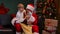 Cute child sits on the lap of santa claus and chooses a gift in a bag for himself. Grandson and grandfather are sitting