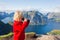 Cute child, standing on top of the mountains and looking down on Reine after climbing Reinebringen treeking path with lots of