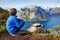 Cute child, standing on top of the mountains and looking down on Reine after climbing Reinebringen treeking path with lots of