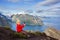 Cute child, standing on top of the mountains and looking down on Reine after climbing Reinebringen treeking path with lots of