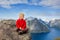 Cute child, standing on top of the mountains and looking down on Reine after climbing Reinebringen treeking path with lots of