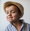 A cute child in a straw hat looks slyly into the frame on a white background