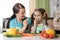 Cute child tasting vegetables as she prepares a meal with their mother in the kitchen