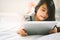 Cute child using a tablet and smiling while sitting on sofa at home