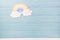 Cute children or baby background, white clouds with rainbow on the blue wooden background