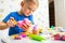 Cute children sitting at the table and plays with playdough