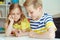 Cute clever schoolchildren are came back to school and studying together at the table