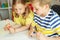 Cute clever schoolchildren are came back to school and studying together at the table