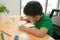 Cute confused smiling boy doing homework, coloring pages, writing and painting . Children paint. Kids draw. Preschooler with book
