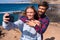 Cute couple of adults taking a selfie together a the beach with the sea at the background - two beautiful and attractive people