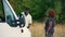 Cute couple during camping. Beautiful Black woman in stripped dress and red afro hairstyle standing in front of white