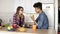 Cute couple eating apple together, sitting in their spacious well lit comfy kitchen.