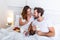 Cute couple having breakfast in bed in the bedroom. Beautiful woman feeding her boyfriend strawberries in bed while having