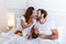 Cute couple having breakfast in bed in the bedroom. Beautiful woman feeding her boyfriend strawberries in bed while having