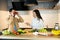 Cute couple are smiling and having fun in kitchen. Happy vegan people are cooking salad using only nutrition and healthy