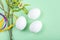 Cute creative Easter composition with white eggs, willow sprigs and colorful ribbons on green background. DIY and kids creativity