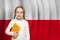 Cute curious little school girl against Polish flag background. Education in Poland concept