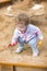 Cute curly baby girl digging in sand on a playground
