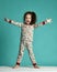 Cute curly baby girl kid in pajama with hands spread screaming on blue mint