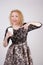 Cute curly blonde girl stands in lace short evening dress and holds a paper Cup of coffee on a white Studio background