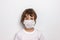 Cute curly boy in white mask on white background. Fight with Coronavirus epidemic concept. Vaccine searching