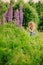 Cute curly child girl smells flower on summer field