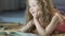 Cute curly girl lying on carpet and reading fairy tales aloud, happy childhood