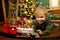 Cute curly-haired boy is playing with a magic toy train at the Christmas tree.