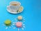 Cute daisy macaroons, colorful French macarons with Chrysanthemum petal flower a cup of tea, delicious sweet dessert on blue