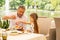 Cute dark-haired girl eating yummy Greek salad with grandfather