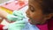 Cute dark skinned African American girl sitting in a red yellow children`s dental chair at the dentist