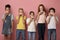 Cute diverse children eating yummy donuts over pink background