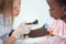 Cute doctor checking skin on shoulders of little afro girl.