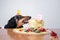 Cute dog breed dachshund, black and tan,  with licking  tongue and hungry for a happy birthday cake with candle number 9,wearing