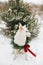 Cute dog in Christmas wreath sitting in snowy winter park. Adorable white swiss shepherd dog in stylish christmas wreath with pine