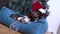 Cute dog dachshund in santa hat after party in the office lies in bed with hangover against the background of the christmas tree.